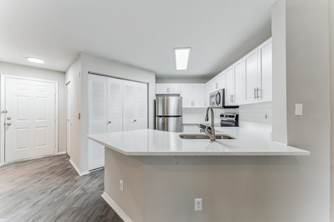 A kitchen with white cabinets and a white countertop.